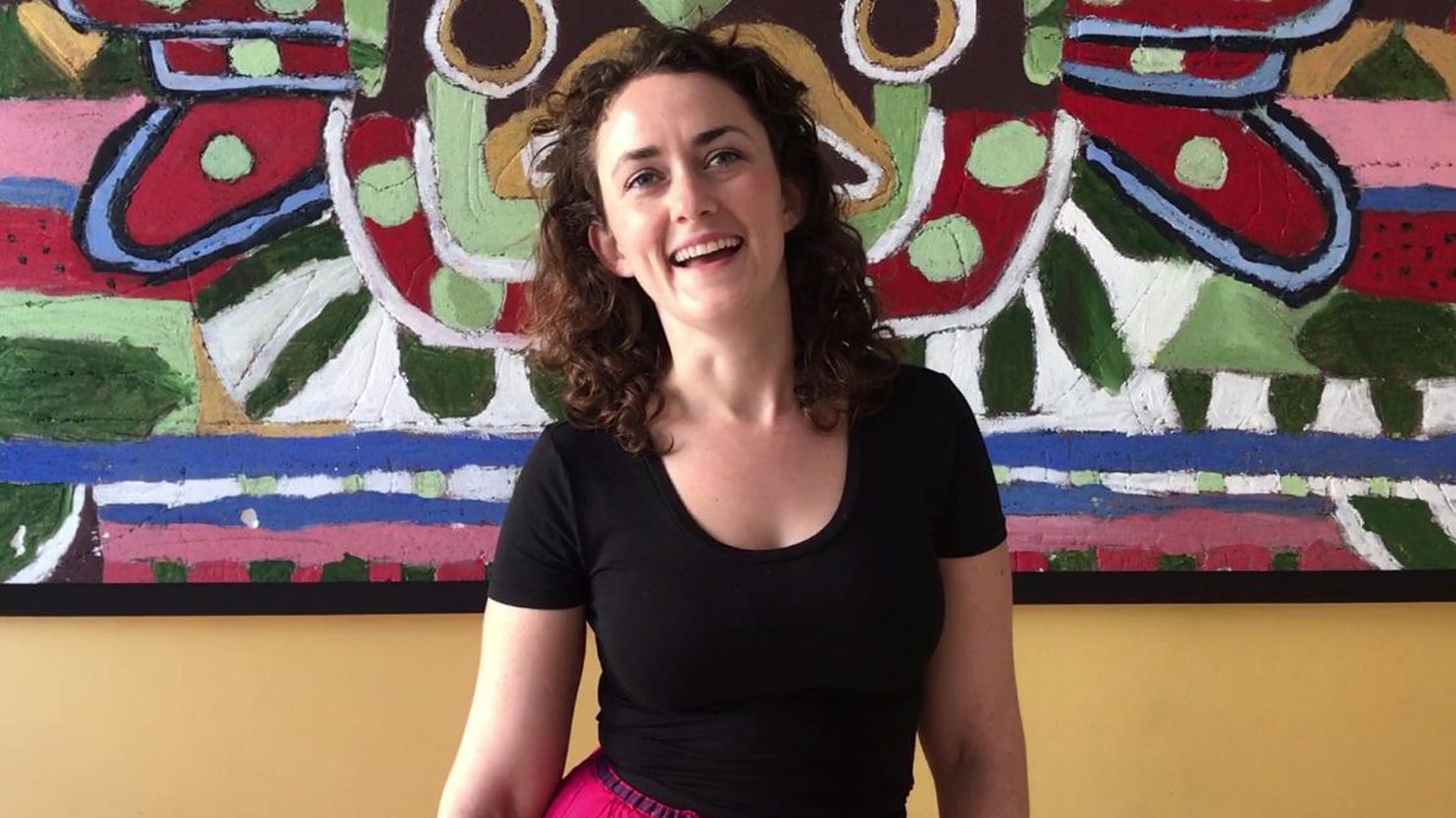 Helen Steer smiling in front of a colorful abstract mural