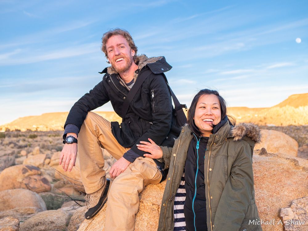 James Simpson and Carrie Leung sitting together on a boulder at sunset