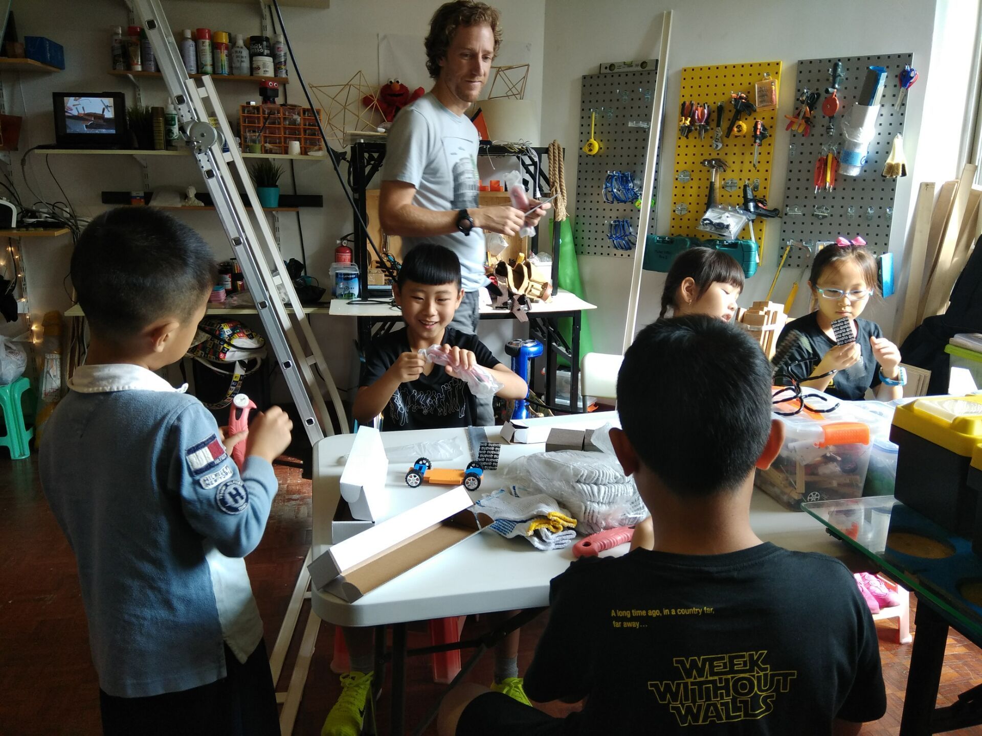 A mentor and young makers building wooden derby cars in the makerspace