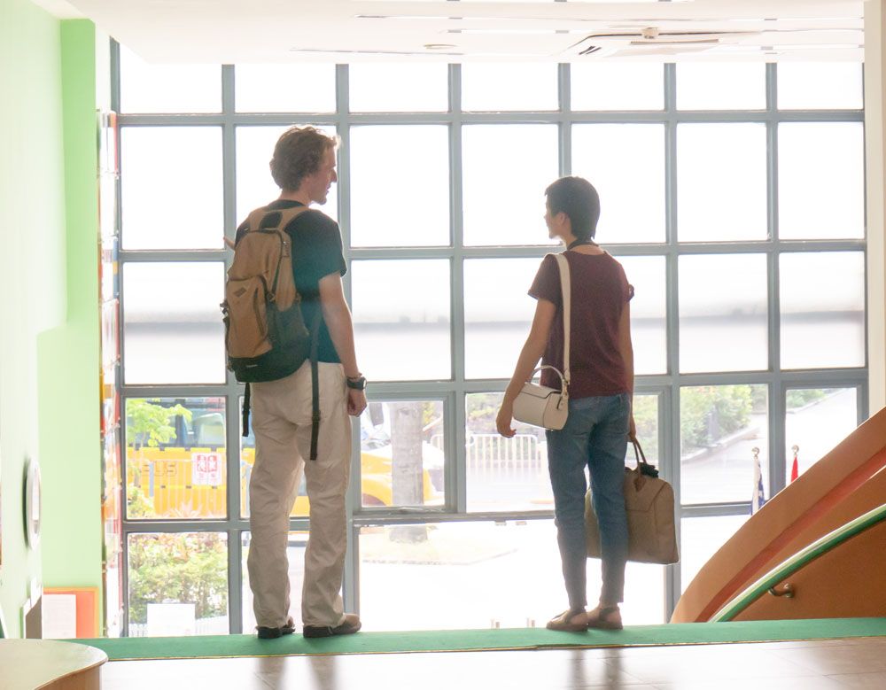 James and Bailey Hu looking out over a school courtyard window