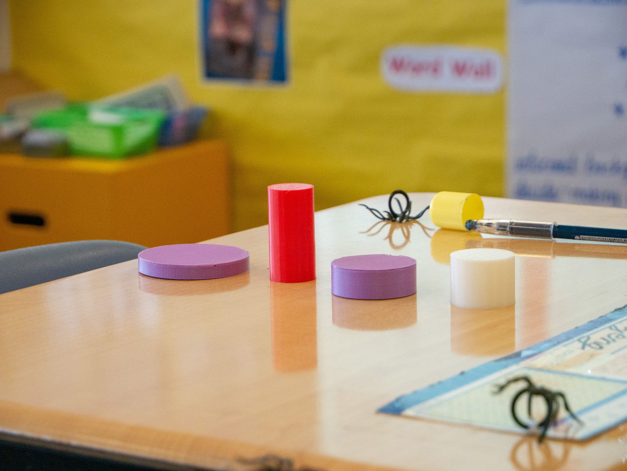 3D-printed cylinder and disc shapes on a classroom desk