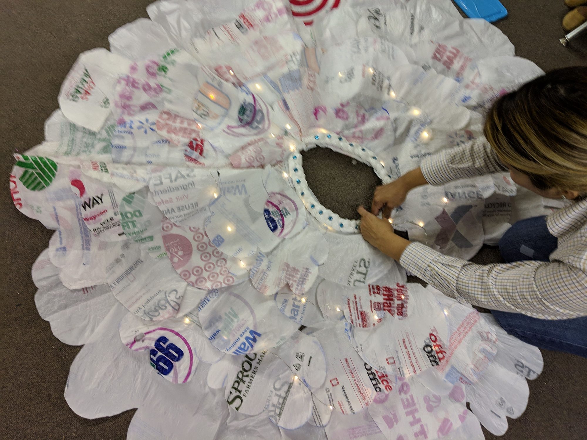Woman assembling a light-up skirt made from cut plastic shopping bags