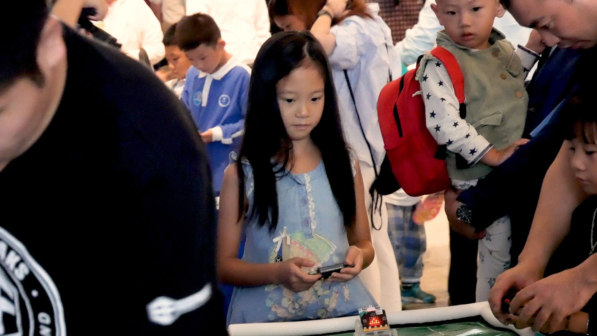A young student watches a micro:bit-controlled car demo