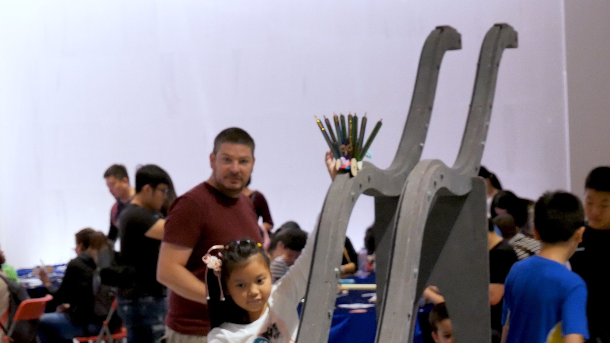 A man and young student pose beside a wooden nerdy derby ramp