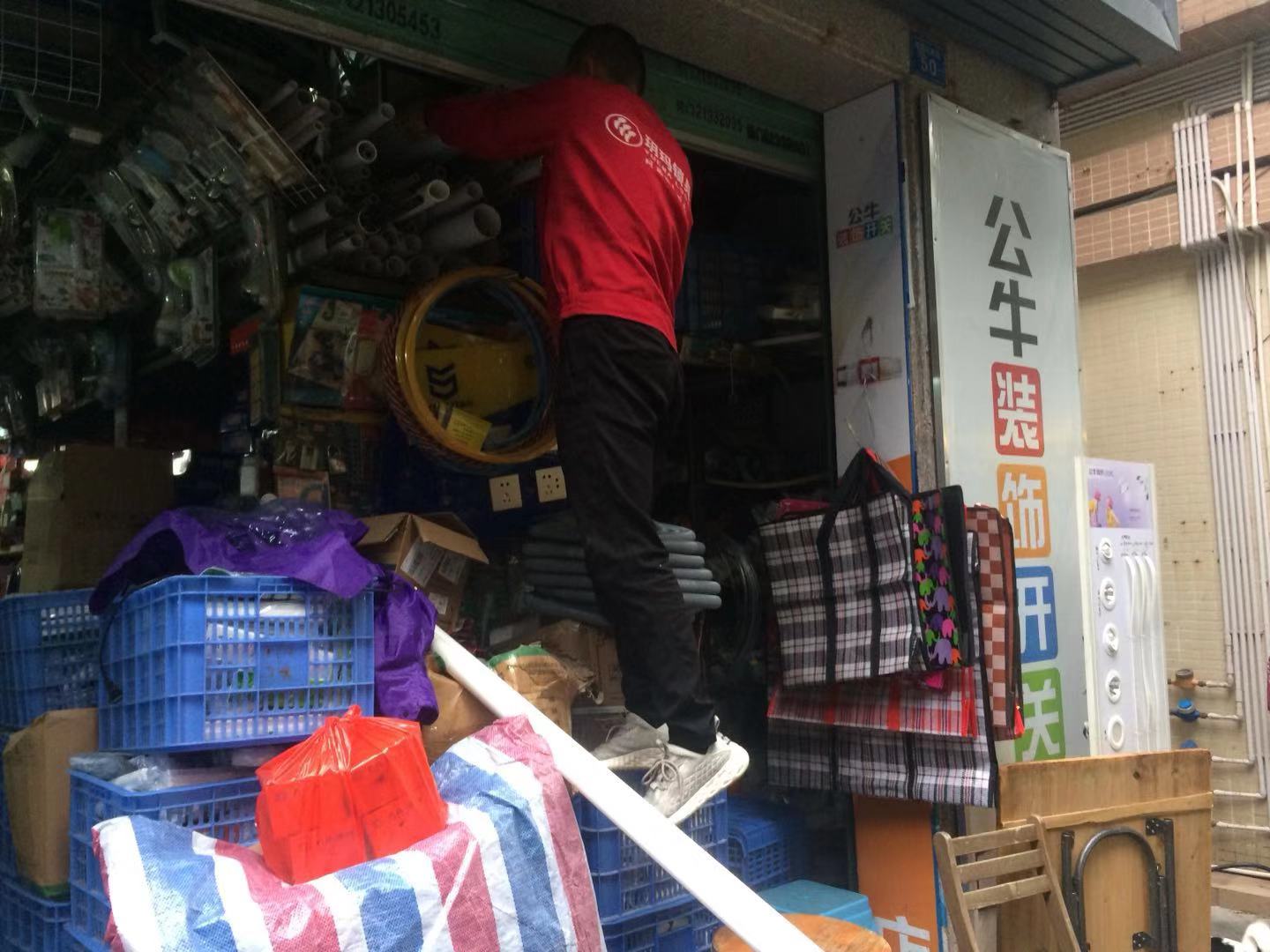 Hardware store employee climbing shelving to reach PVC pipe stock