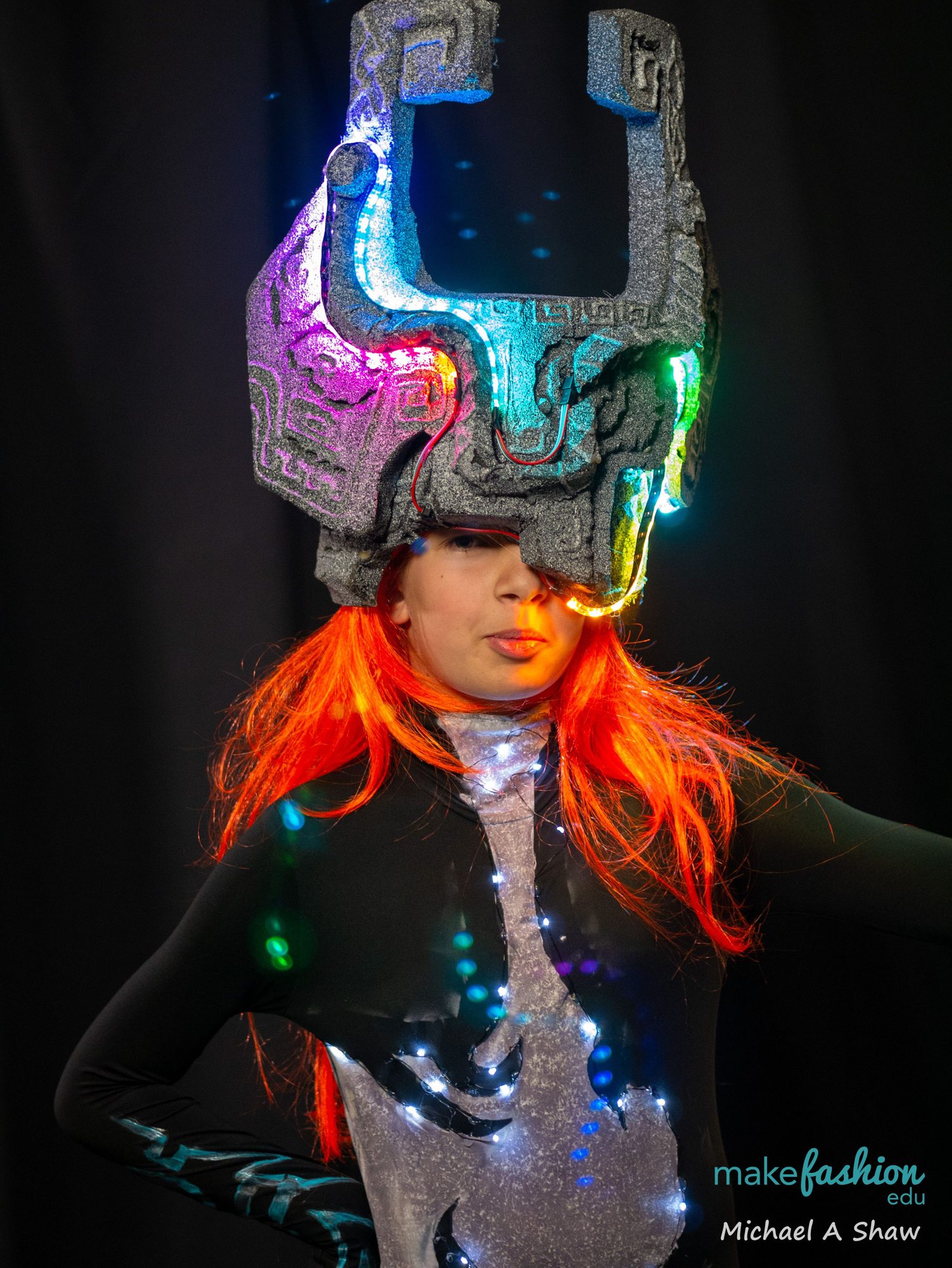 Student wearing a glowing spiked LED helmet and orange wig