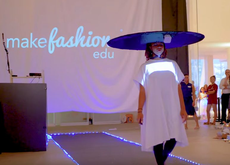 Runway model wearing an illuminated wide-brim hat and dress