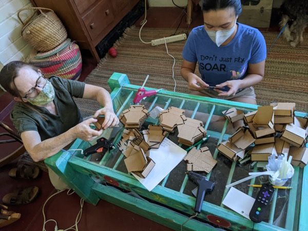 Twila and Elisa Busby assembling cardboard reflector frames at a table