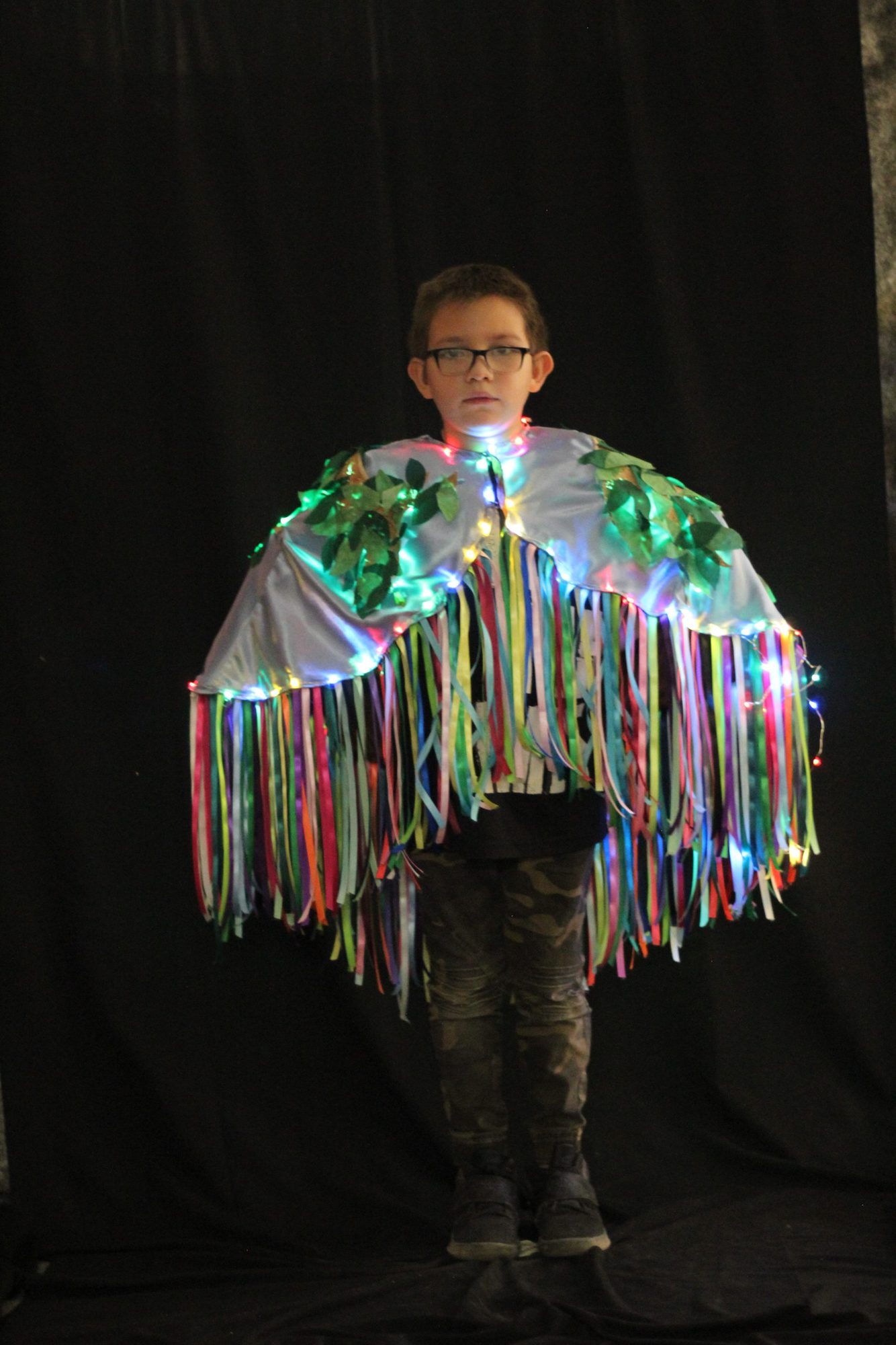 Student wearing a light-up ribbon and leaf poncho costume