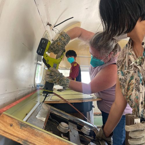 Mobile Makerspace chapter 4: three volunteers removing old paneling inside the trailer