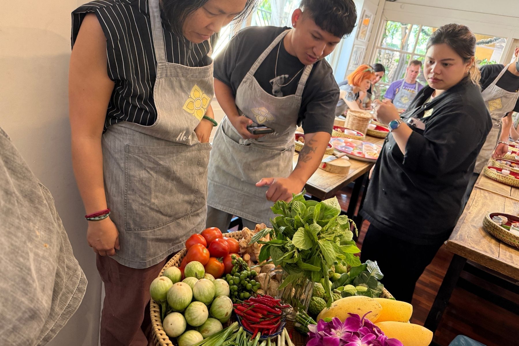 Cooking class group gathered around a basket of fresh vegetables