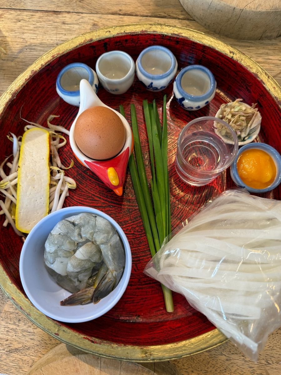 Tray of Thai cooking ingredients including egg, shrimp, and rice paper