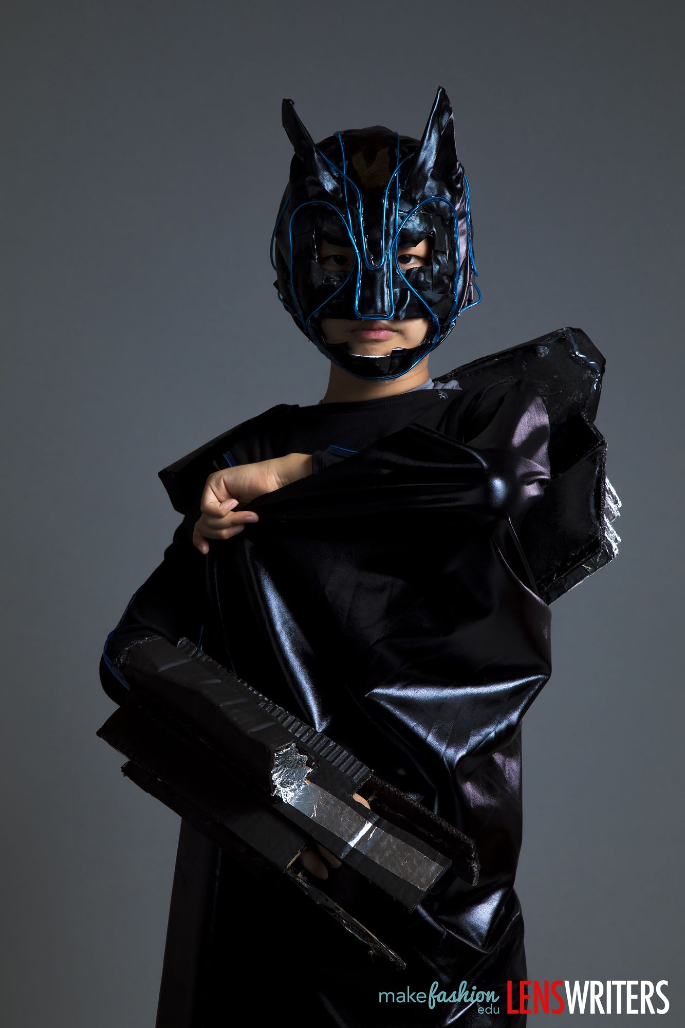 Student model in black suit with LED-accented horned mask with cyan striped lines