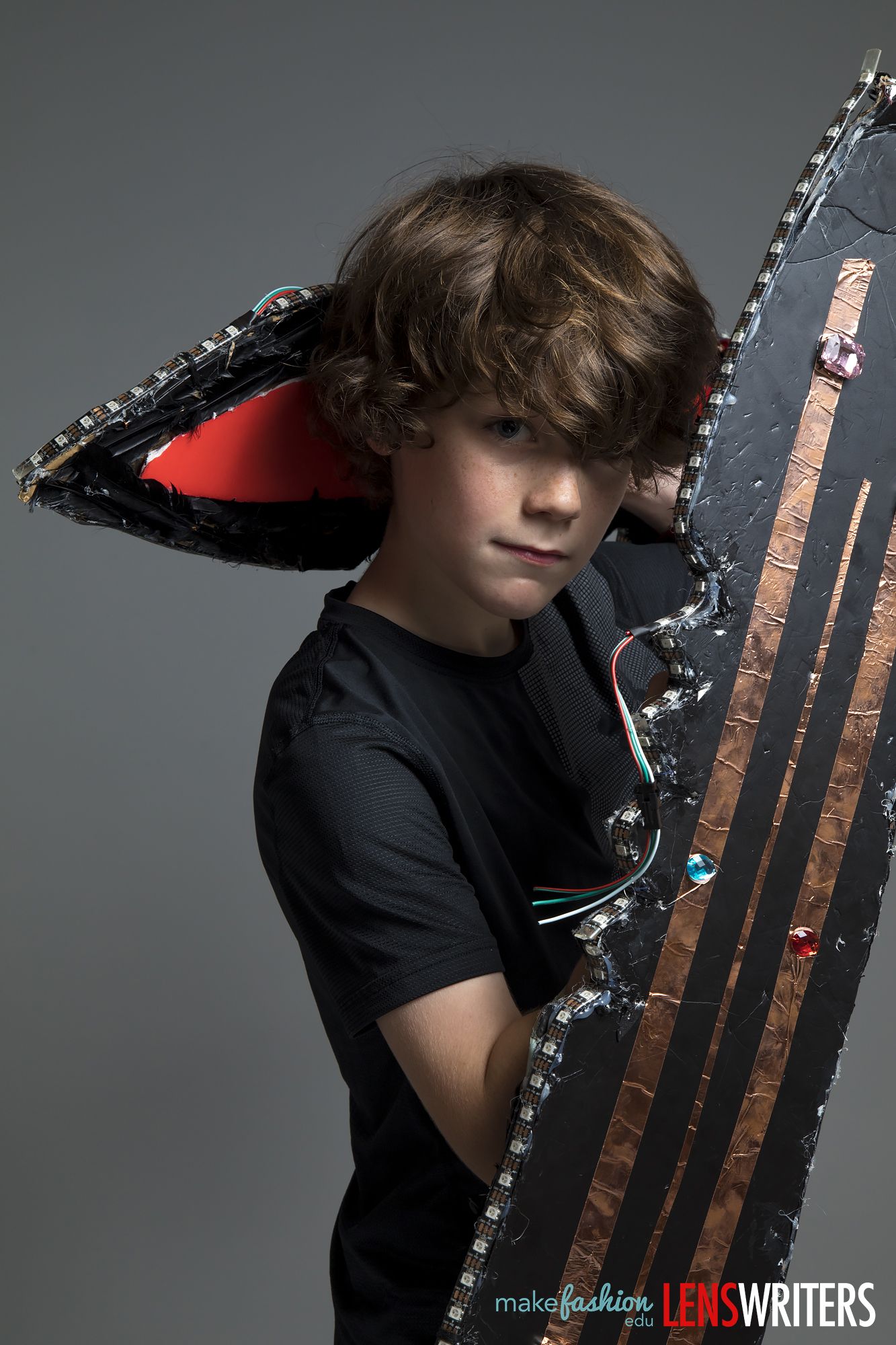 Student model holding a large black LED-edged wing panel with copper stripes