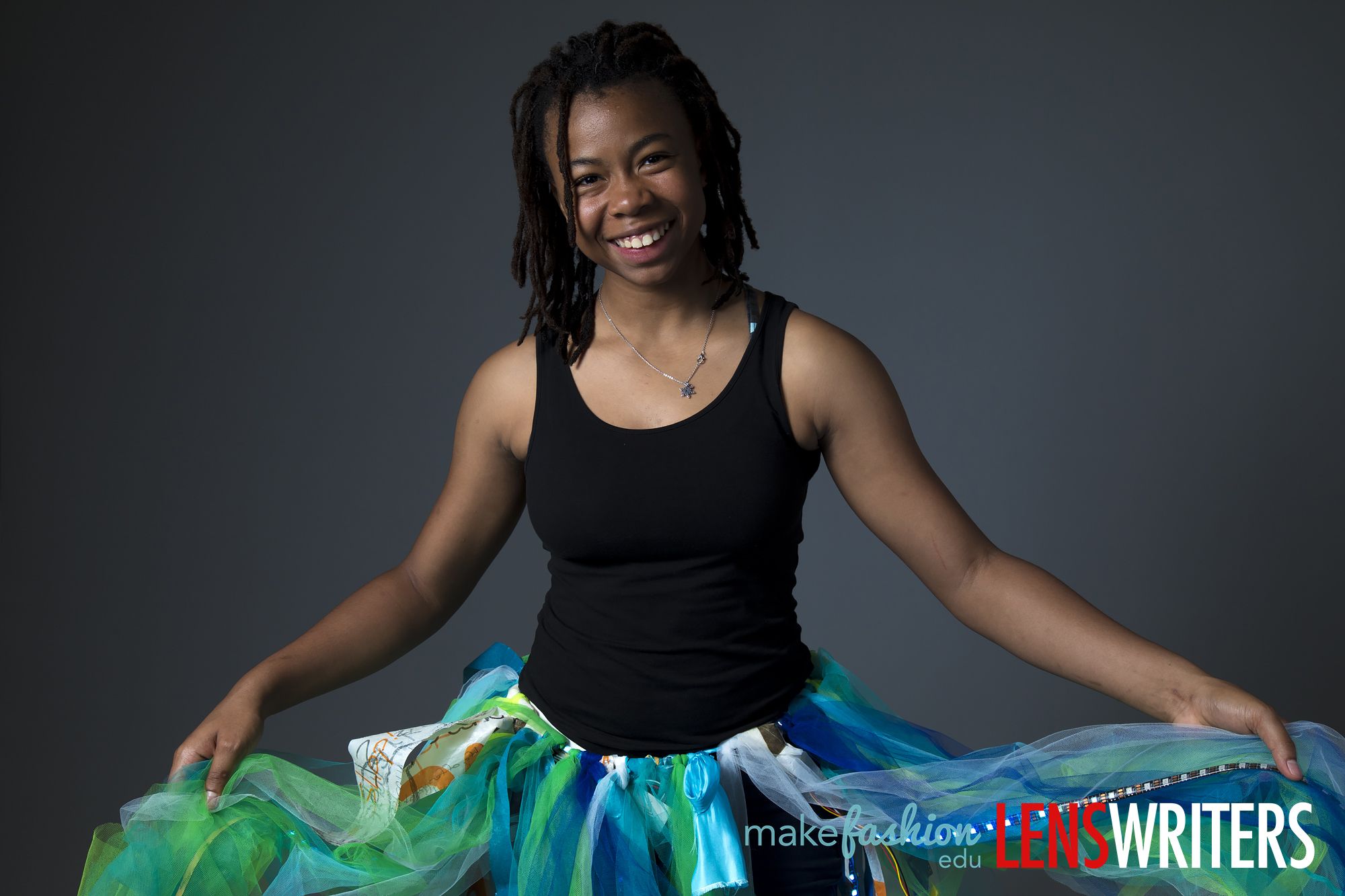 Student model in black tank wearing LED-embellished colorful tulle skirt with blue and green tones