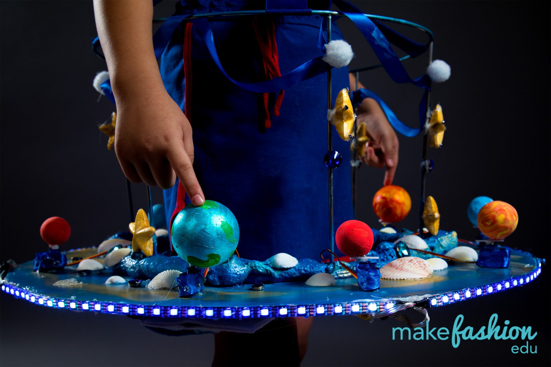 Wearable planetarium with painted planet spheres on stands and a blue LED-lit rim