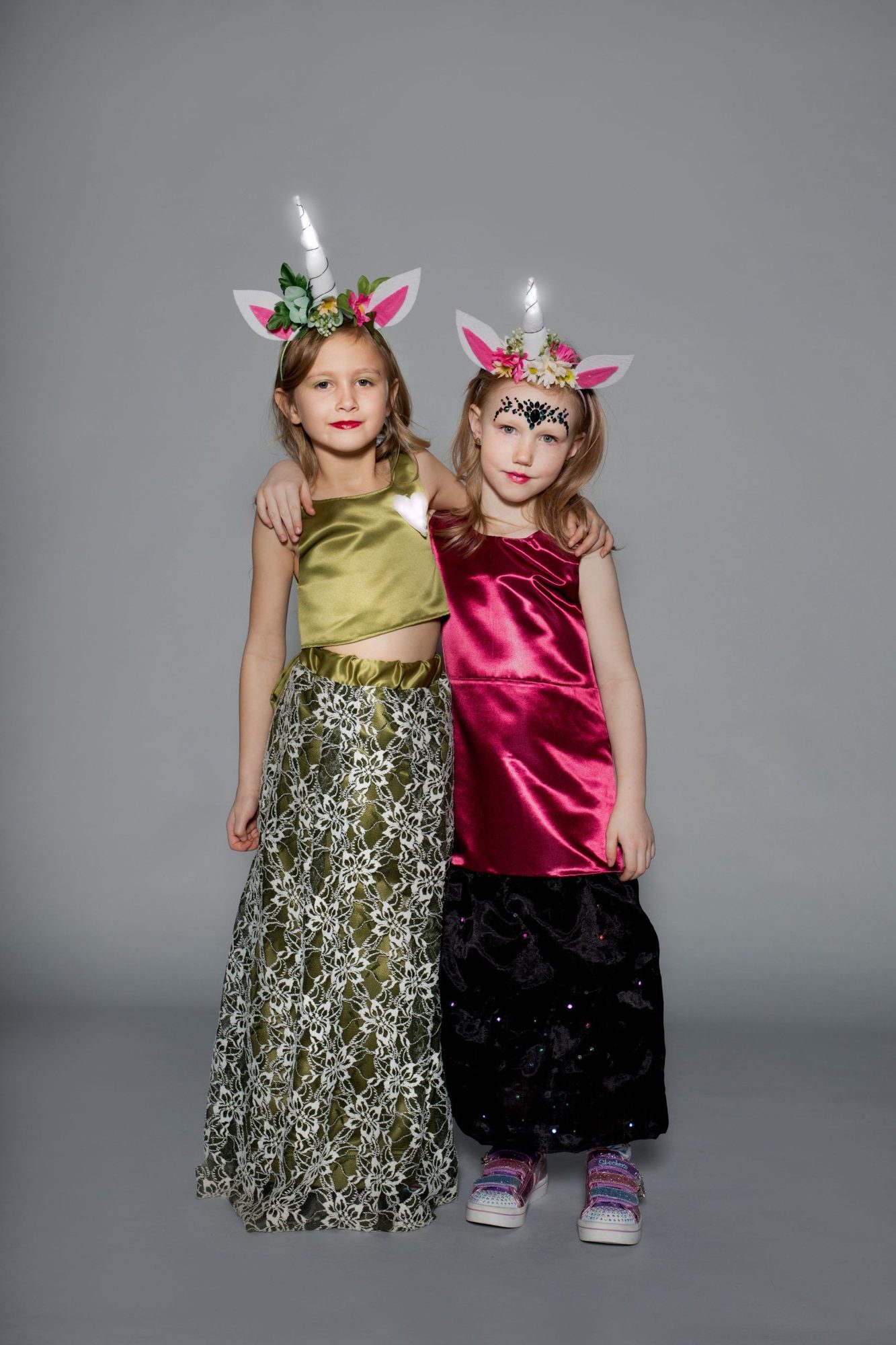 Two students in elegant dresses wearing floral unicorn crowns