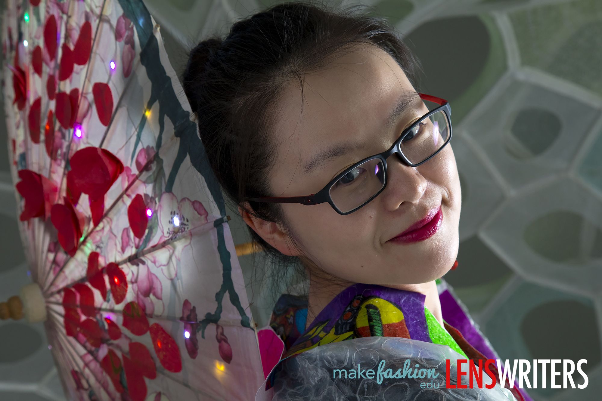 Student model holding floral parasol with red blossoms and colorful LED lights