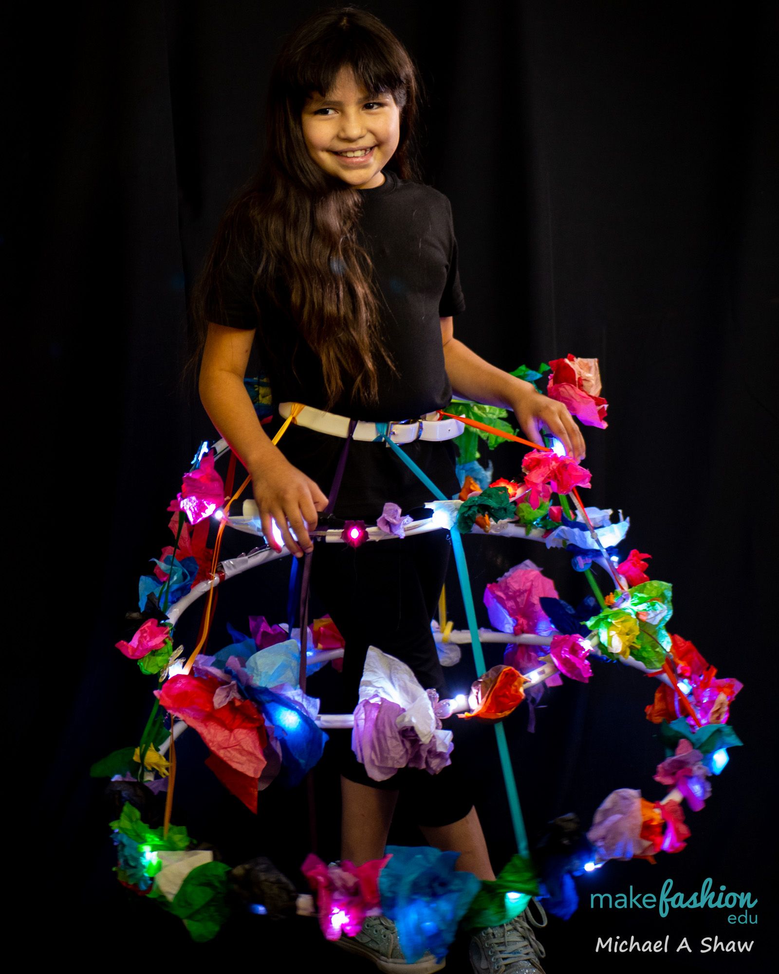 Student model inside a hoop skirt frame covered in glowing paper flowers