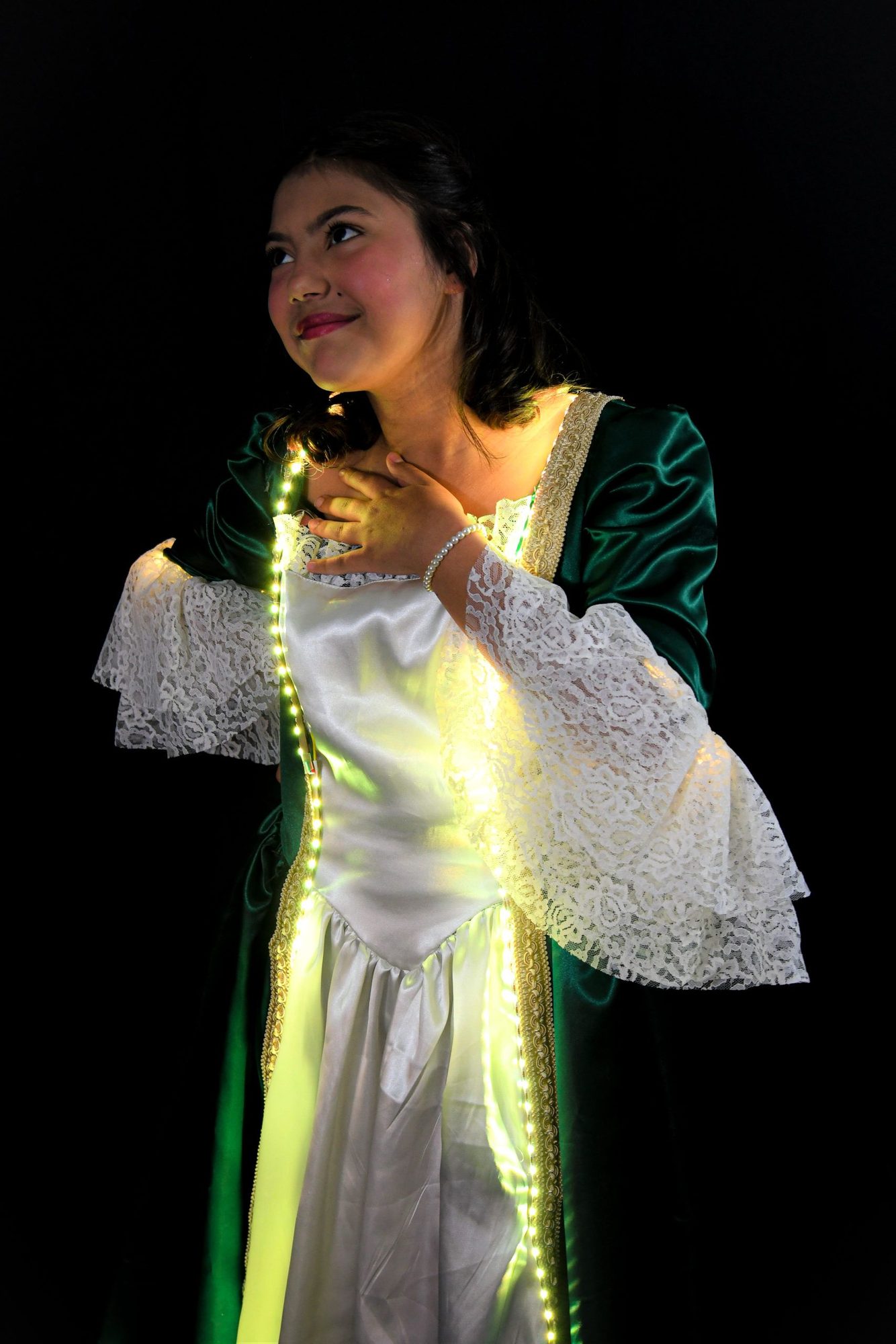 Student in elegant green and white dress with glowing golden LED accent
